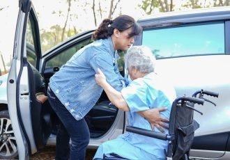 Help and support asian senior or elderly old lady woman patient sitting on wheelchair prepare get to her car : healthy strong medical concept.